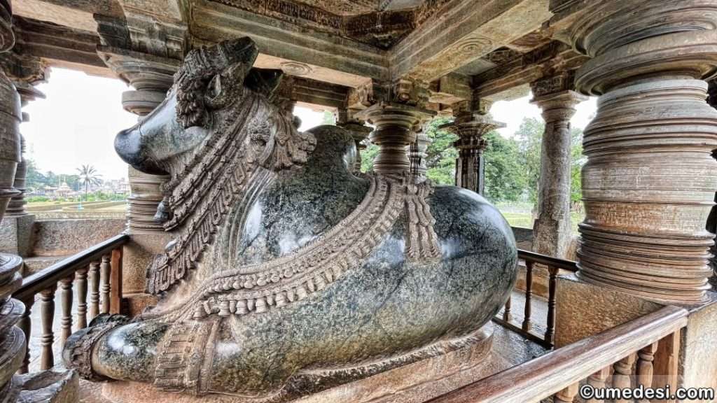 Side view of Nandi sculpture at Hoysaleswara Temple, surrounded by intricately carved pillars.