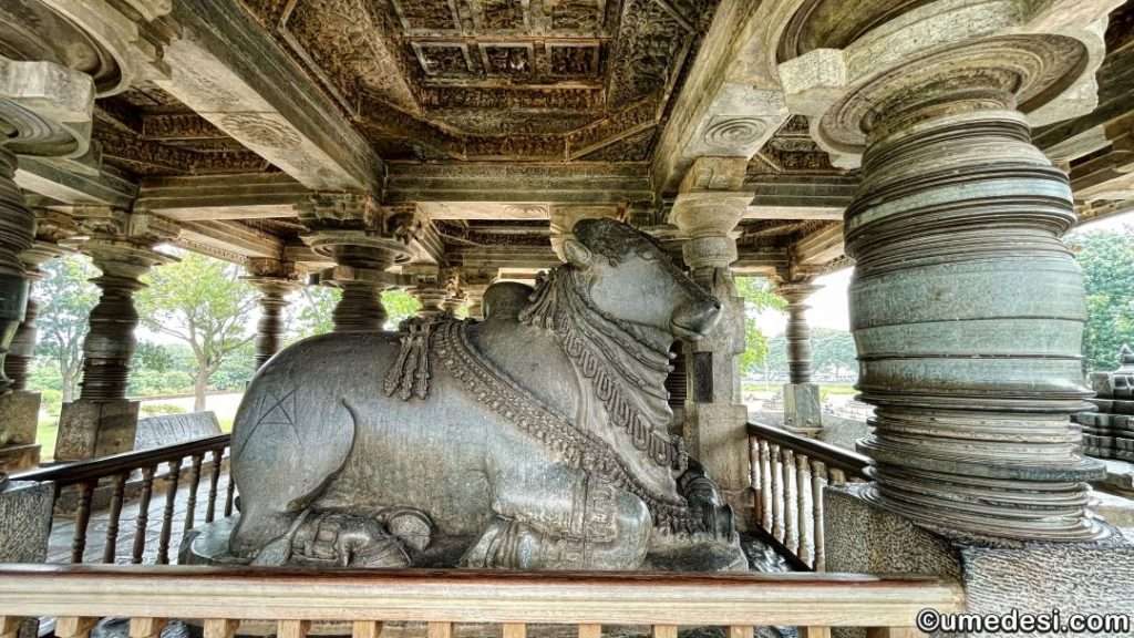 Stone Nandi sculpture housed within a pavilion at Hoysaleswara Temple.