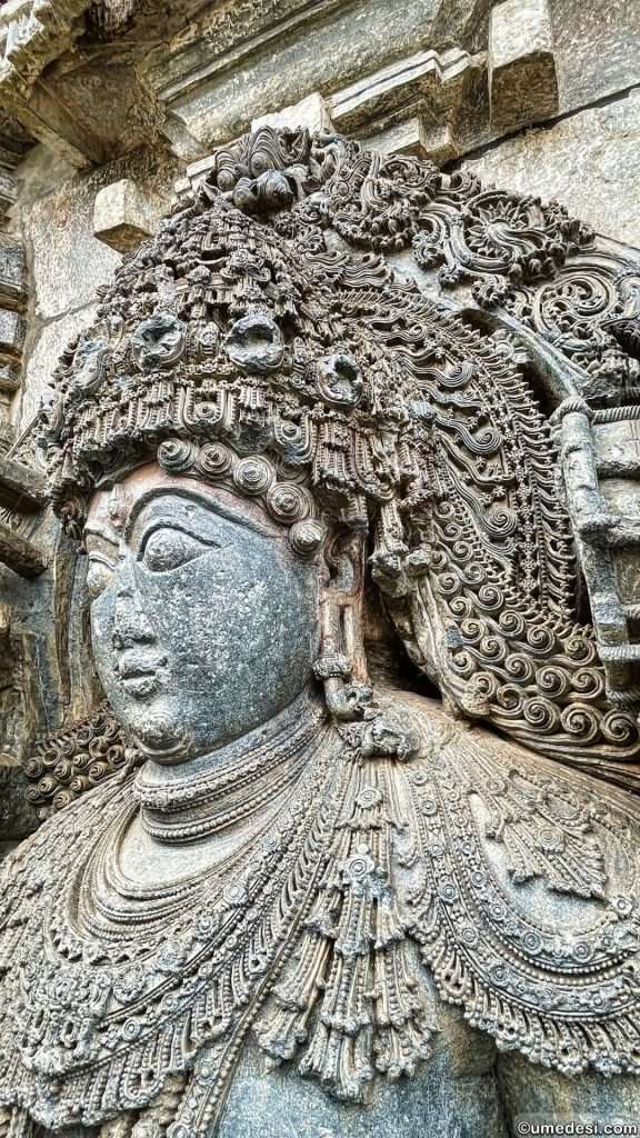 Magnificent detailing of a deity's headgear and facial features in a Hoysaleswara Temple sculpture.