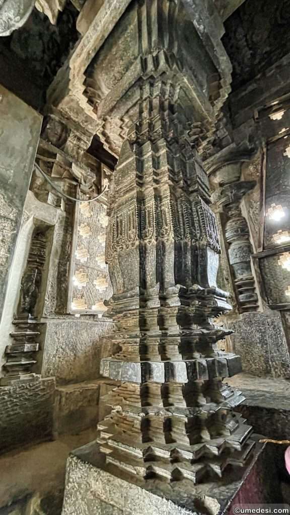 Ornate pillar inside Hoyasaleswara Temple with geometric and floral carvings under ambient lighting.