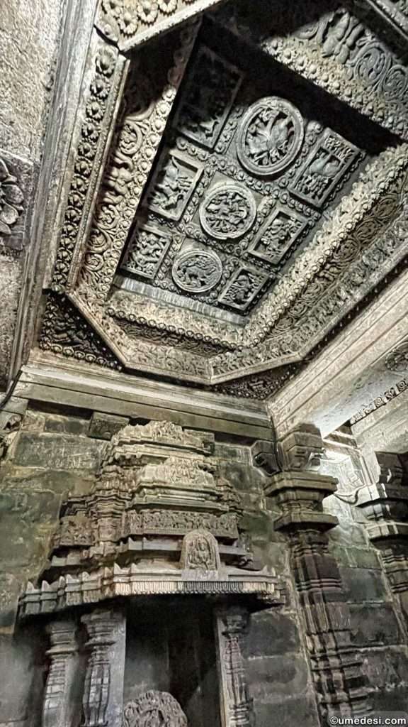 Carved temple ceiling featuring panels of mythological figures and floral designs at Hoyasaleswara Temple.