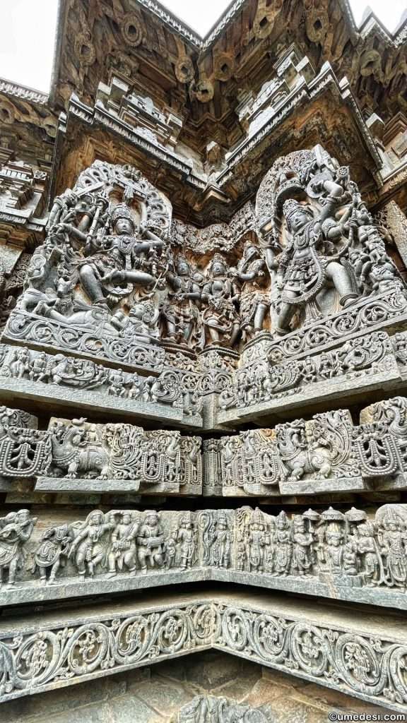 A corner of Hoysaleswara Temple featuring layers of carved panels and mythological figures.