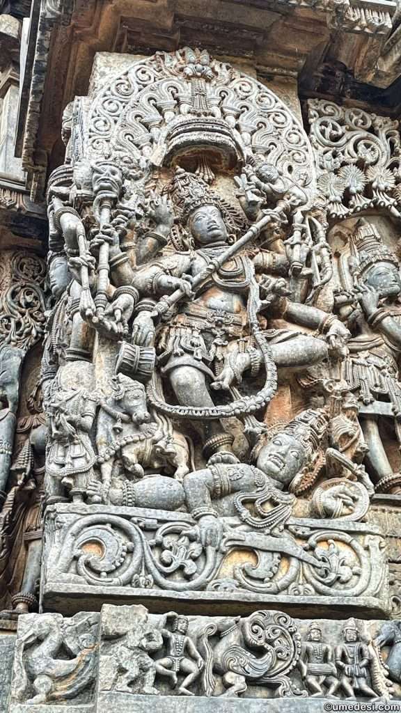 Detailed sculpture of Lord Shiva surrounded by intricate decorative elements at Hoysaleswara Temple.
