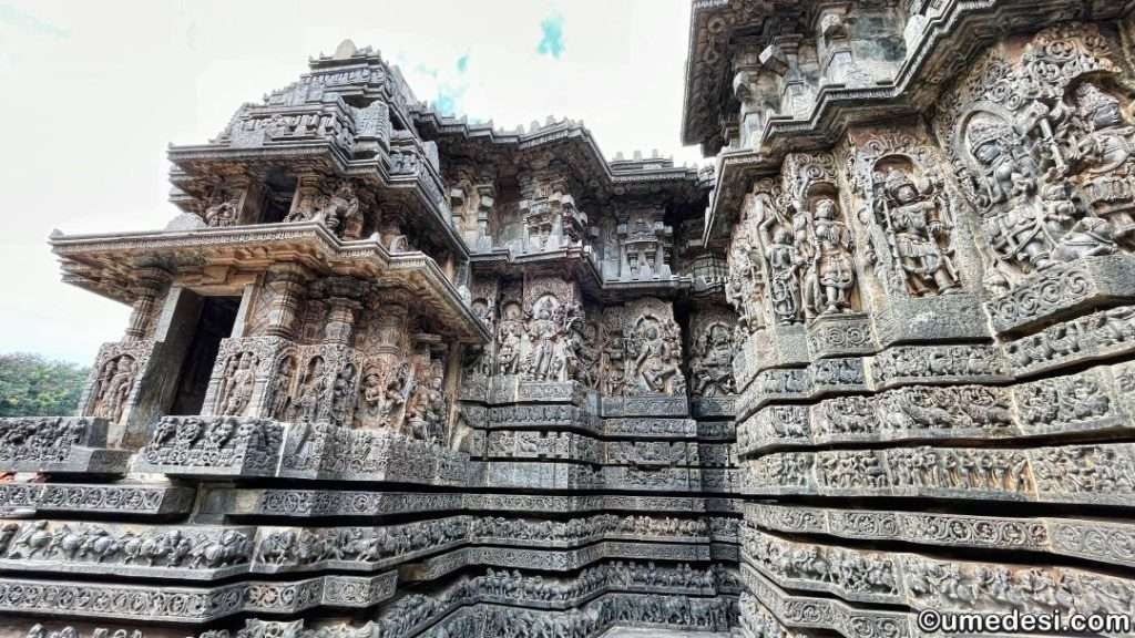 Wide-angle view of Hoysaleswara Temple's exterior featuring layered carvings and divine figures.
