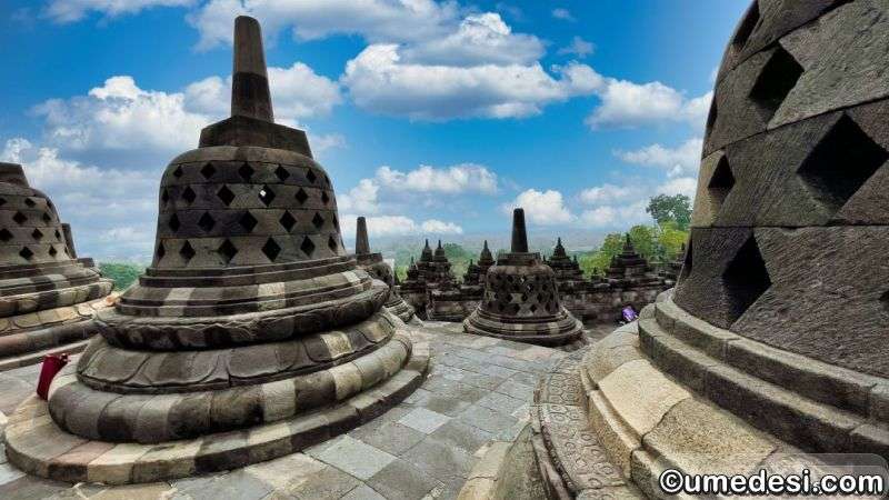 Closer angle of Borobudur’s perforated stupas on the upper terrace, showing layered stones and distant greenery below.