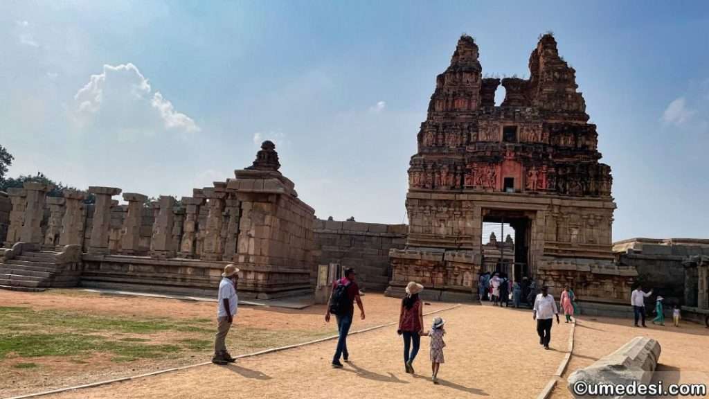 Tourists walking towards the gopuram entrance of Vijaya Vittala Temple in Hampi.