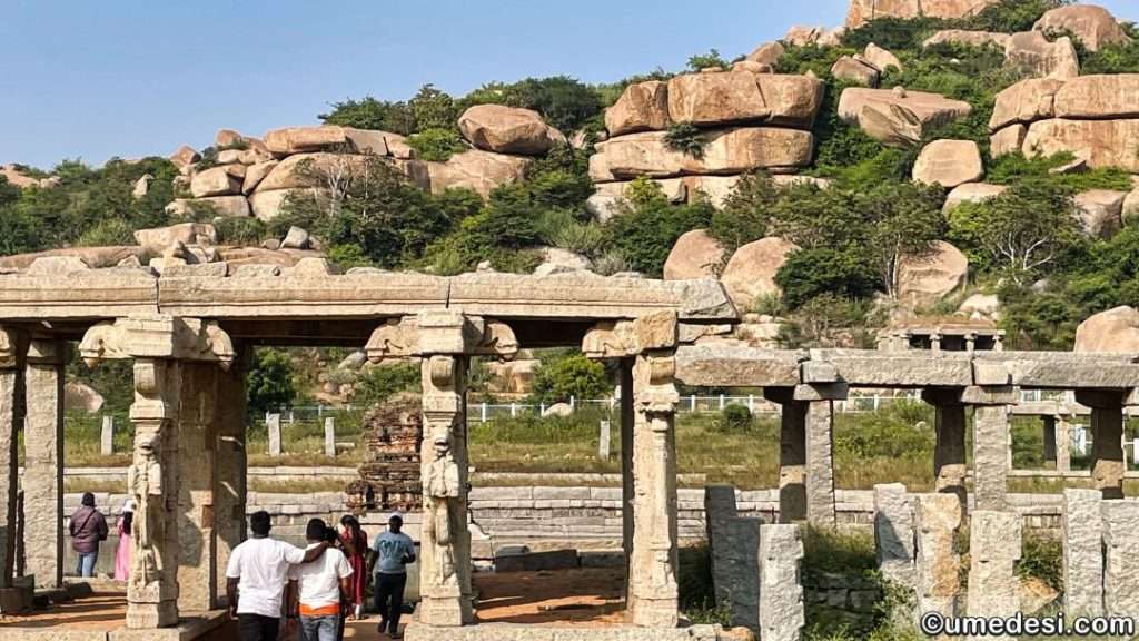 Rocky terrain with behind an old temple between the stores in the Hampi Bazaar.
